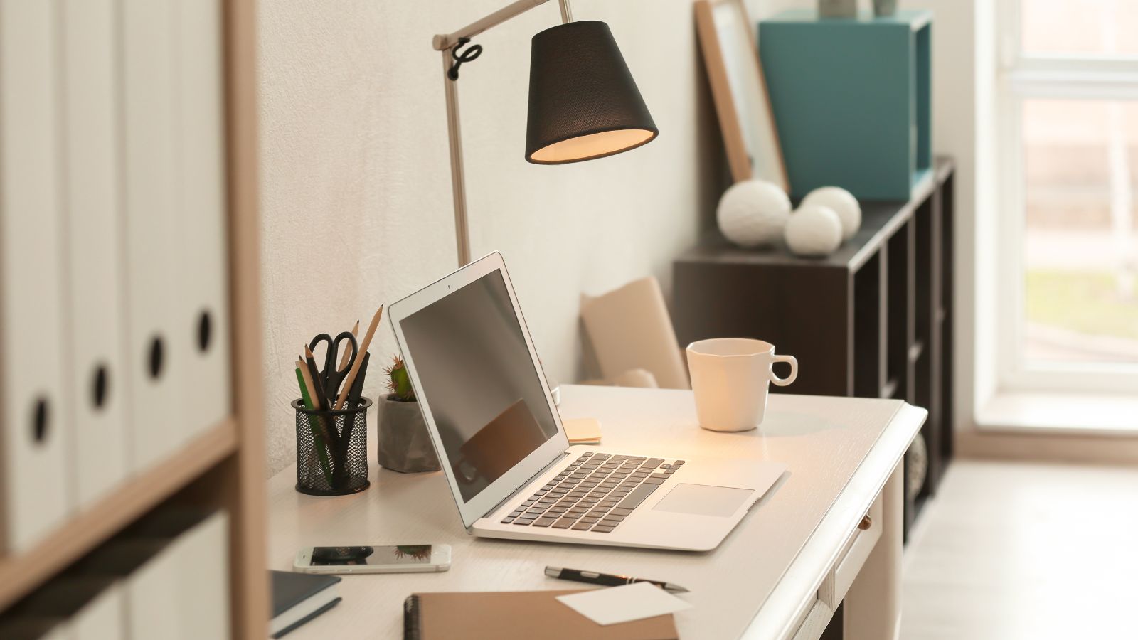 A home office featuring a laptop, coffee mug, and lamp on a desk