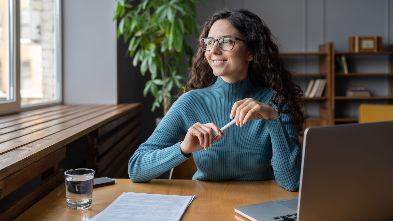 A home office worker looking out of her window and smiling